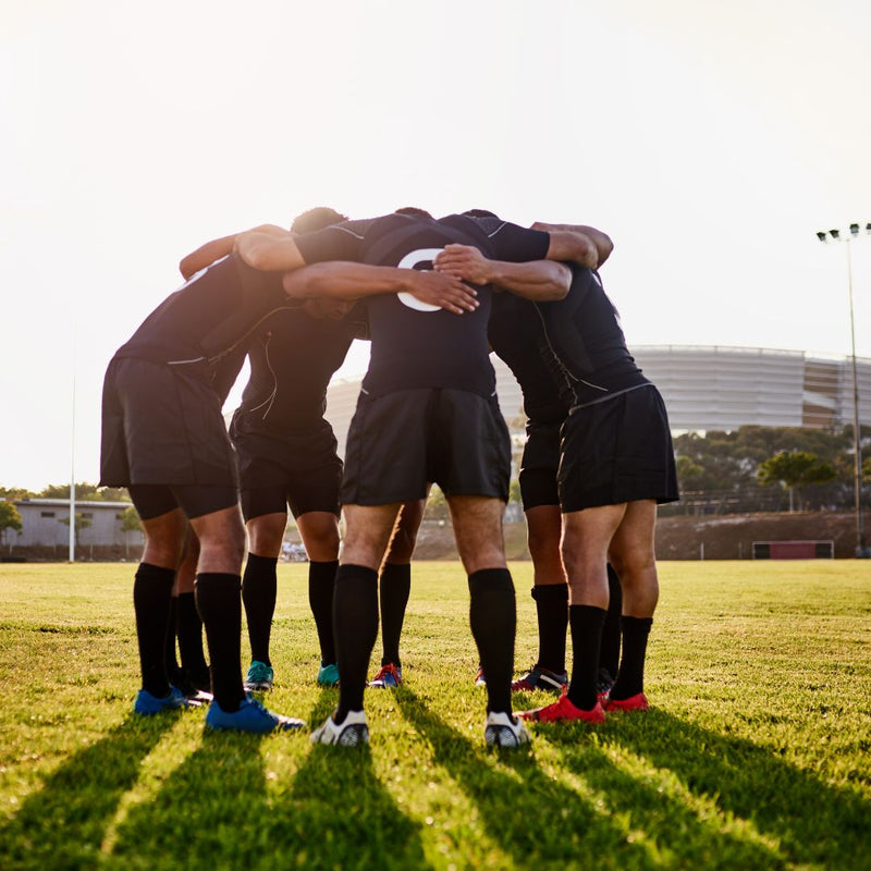 Soccer players in a huddle on a grass field