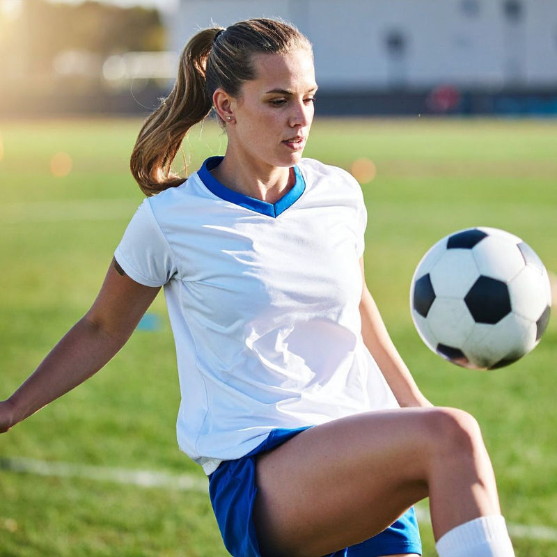 Woman playing soccer on a field with a blurred background